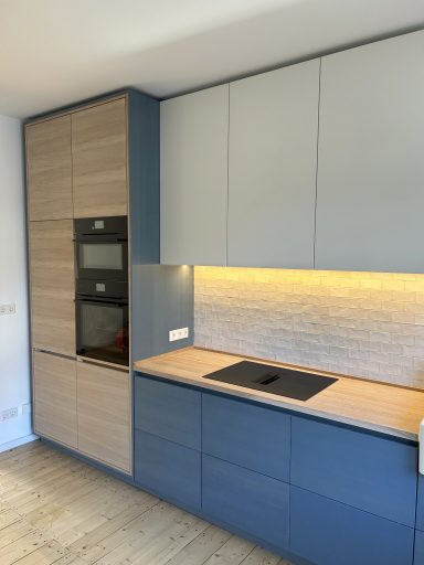 Küche Eine Küche aus blau lackierten Eichefurnierplatten. Unter den Hängeschränken ist eine LED-Leiste eingesetzt.